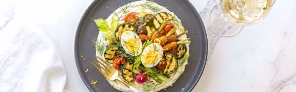 A colorful mix of fresh and grilled vegetables on whipped goat cheese in a plate.