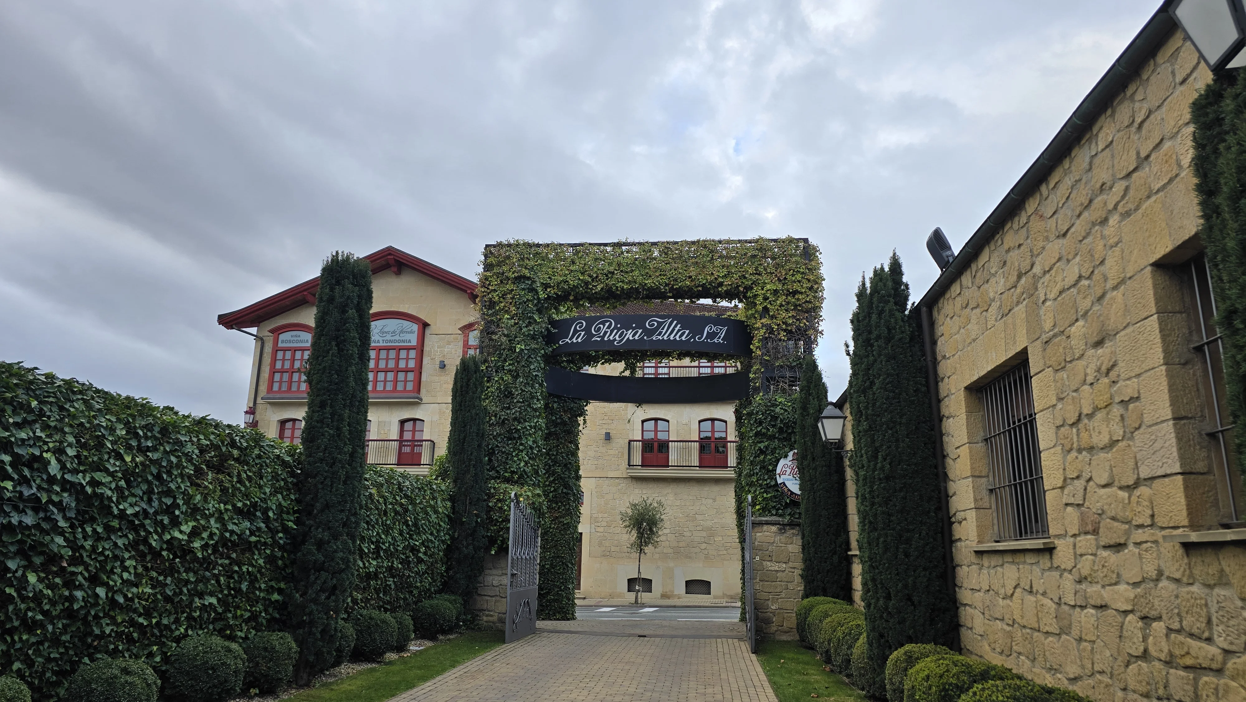 The entrance gate of La Rioja Alta looking across the road toward R. López de Heredia's red-trimmed facade.